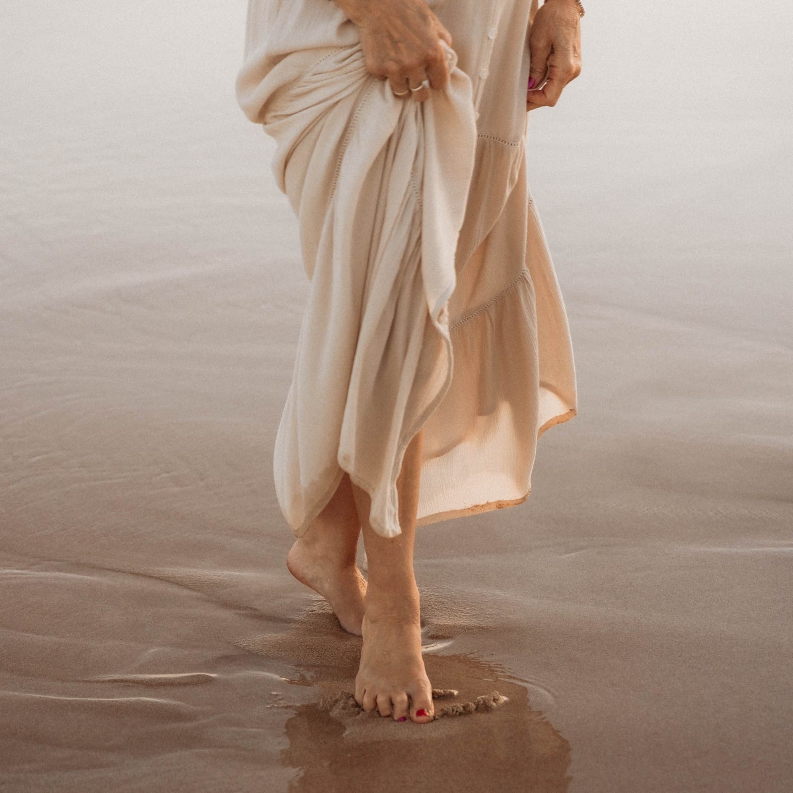 A serene moment captured: Val Hood, an Evidential Medium, walks on the beach, embracing the calming ocean breeze.